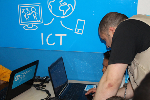 SOS co-worker shows young visitor at ICT Corner how to use the computer